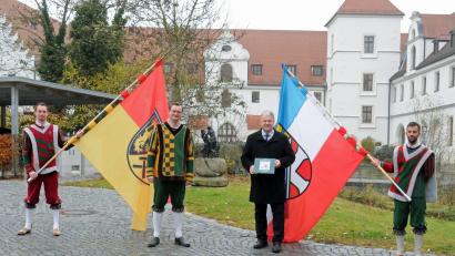 Bild: Christine Hollederer/exb
Die Fahnenschwinger Johannes Piehler, Peter Kick und Johannes Hager (von links) überreichten die Chronik an Landrat Richard Reisinger.