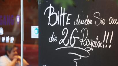 Symbolbild: Oliver Berg/dpa
Ein Schild, das auf die 2G Regeln hinweist, hängt an einem Cafe.