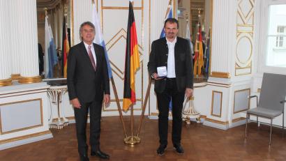 Bild: Regierung der Oberpfalz/Schmied/exb
Regierungspräsident Axel Bartelt (links) überreicht Johann Wiesnet die Kommunale Verdienstmedaille in Bronze.