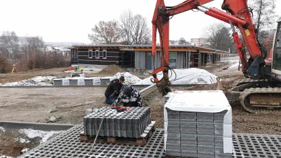 Bild: Portner
Am Zugangsbereich zum neuen Kinderhaus wird mit Hochdruck gearbeitet. Die Pflasterer der Firma Liegl-Bau aus Leuchtenberg verlegen die Rasengittersteine für die Parkbuchten.