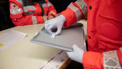 Symbolbild: Marijan Murat/exb
Eine ehrenamtliche DRK-Helferin nimmt in einer Teststation einen Corona-Schnelltest von einem Tablett.