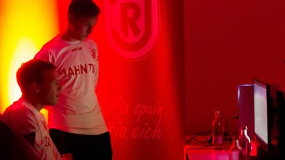 Bild: SSV Jahn Regensburg
Sven Kopp (sitzend) in Aktion an der Konsole, Leon Kipry als Beobachter und Tippgeber: Die beiden Fußballer der SpVgg SV Weiden zocken in ihrer Freizeit in der "Virtual Bundesliga" für den SSV Jahn Regensburg.