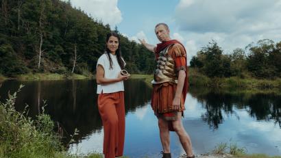 Bild: Sabine Finger/exb
Cäsar (Thorsten Krohn) trifft am Rubikon eine folgenschwere Entscheidung. Für diesen Moment in der Geschichte haben die Mitarbeiter der IFAGE Filmproduktion nach einem passenden Fluss gesucht: Die Naab in der Nähe des Anglerheims in Nabburg entpuppte sich als ideal. Clarissa Corrêa da Silva (links) sucht dort den Römer mit Hilfe der Zeitmaschine persönlich auf, um ihn zu interviewen.