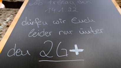 Bild: Robert Michael
Auf einem Schild wird vor einem Cafe auf die 2G-plus-Regel hingewiesen. Wer genesen ist, behält diesen Status künftig nur noch drei statt sechs Monate. Foto: Robert Michael/dpa-Zentralbild/dpa