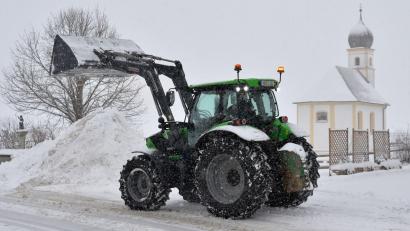 Bild: Uwe Lein/dpa
Mit einem Radlader räumt ein Anwohner in dichtem Schneefall eine Straße im Landkreis Miesbach.