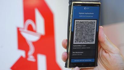 Symbolbild: Oliver Berg/dpa
Der digitale Impfnachweis ist vor dem Apotheken-Logo auf einem Smartphone zu sehen.