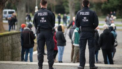 Symbolbild: Julian Stratenschulte
Polizisten stehen am Rande einer Corona-Demo.
