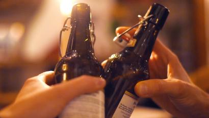 Symbolbild: Angelika Warmuth/dpa
Zwei Gäste stoßen mit Bier in der Flasche an.