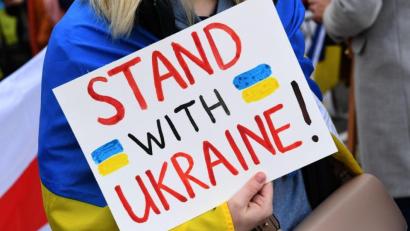 Bild: Felix Hörhager/dpa
Eine Demonstrantin steht mit einem Plakat "Stand with Ukraine! " steht bei einer Demo.