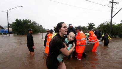 Bild: Jason O'brien/AAP/dpa
Eine Frau im australischen Lismore sucht mit Baby Schutz vor den Fluten.  Sintflutartiger Regen hat die schweren Überschwemmungen im Osten Australiens weiter verschärft.