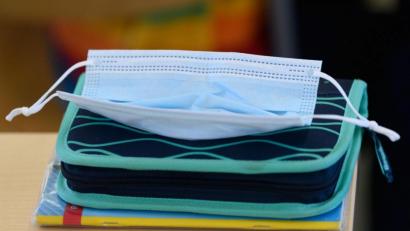 Bild: Robert Michael/dpa-Zentralbild/dpa/Symbolbild
Eine OP-Maske liegt in einem Klassenzimmer auf einem Federmäppchen.