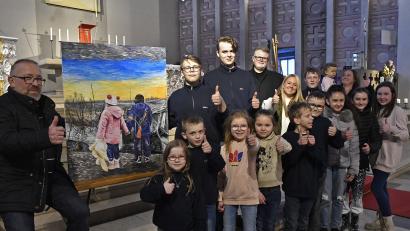 Bild: Petra Hartl
Dieses Motiv ist sinnbildlich für die aktuelle Zerrissenheit der Ukraine. Auf dem Foto sind neben dem Künstler Piotr Chamczyk (links neben dem Bild) und Seelsorger Maciej Kolanowski einige der Ministranten und Gruppenleiterinnen zu sehen, die am Sonntag bei ihrem Kuchenverkauf 1140 Euro eingenommen haben.