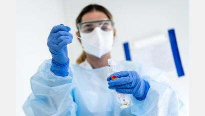 Symbolbild: Jean-Christophe Bott/KEYSTONE/dpa
Eine Krankenschwester steckt eine Probe mit einem Nasenabstrich eines Patienten, der auf das neuartige Coronavirus getestet wird, in einen Behälter.