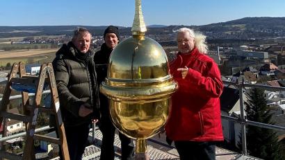 Bild: ads
Die Turmspitze von St. Barbara glänzt wieder golden. Architekt Heinrich Schwirzer, Restaurator Dietmar Feldmann und Zimmerer Alexander Bachmann (von links) richten die Spitze ein