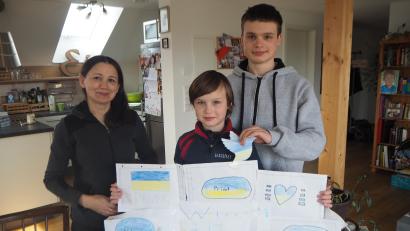 Bild: bl
Voller Stolz präsentiert der zehnjährige Aleksander die Bilder, die seine neuen Klassenkameraden in Pfreimd für ihn gemalt haben. Sein älterer Bruder Andrei (rechts) hatte gerade seinen ersten Schultag in der Nabburger Realschule. Zusammen mit ihrer Mutter Valentina Burenko sind die Geflüchteten aus Kiew bei der Familie Eichinger in Pfreimd untergekommen.