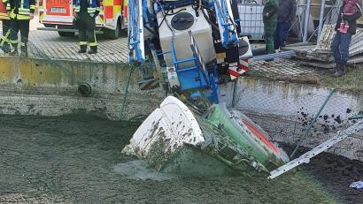 Bild: Yvonne Jackewitz/Feuerwehr Wald/dpa
Feuerwehrleute stehen neben einer Güllergrube, in die ein Traktor mit Anhänger gestürzt ist.