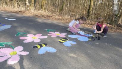 Bild: rn
Blumen und Bienen auf grauem Asphalt: Mit einer Malaktion treten Eschenbacher Kinder für den Umweltschutz ein.