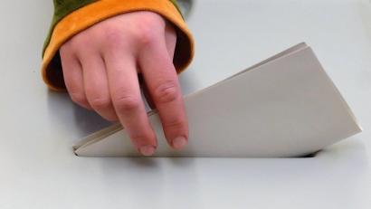 Symbolbild: Peter Endig
Eine jugendliche Hand steckt einen Stimmzettel in eine Wahlurne.
