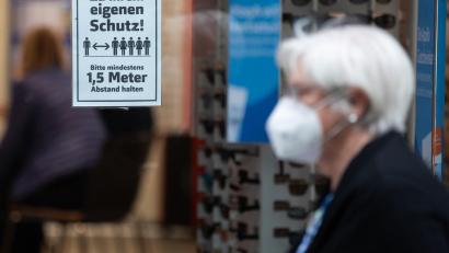 Bild: Tom Weller
Eine Frau mit Mundschutz geht an einem Schild mit der Aufschrift "Zu Ihrem eigenen Schutz! Bitte mindestens 1,5 Meter Abstand halten" vorbei, welches in einem Schaufenster klebt.