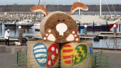 Symbolbild: Bernd Wüstneck/dpa
Eine Osterhasen-Skulptur aus Strohballen steht eingezäunt im Boddenhafen.