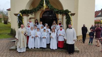 Bild: dlu
Die Erstkommunionkinder mit Pfarrer Roland Klein und den Ministranten vor der Pforte der Pfarrkirche St. Petrus und Paulus in Neukirchen.