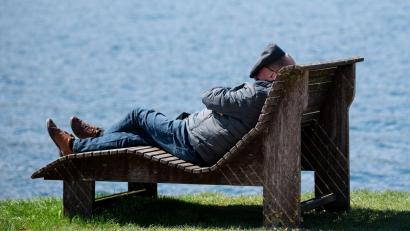 Bild: Sven Hoppe/dpa/Symbolbild
Ein Mann liegt am Ufer des Tegernsees in der Sonne.