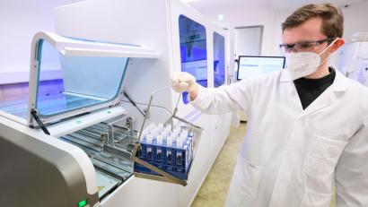 Symbolbild: Julian Stratenschulte
Ein Labormitarbeiter bestückt ein Gerät für die molekulare Diagnostik mit Patientenproben.