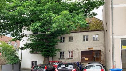Bild: Gabi Schönberger
Das ehemalige Milchladl in der Scheibenstraße 9 hätte eine Sanierung und neue Nutzung verdient. Zumindest der Platz vor dem Haus ist als Parkplatz beliebt. Die Stadt sucht für das Gebäude und den angrenzenden Flurerturm (vom Baum verdeckt) einen Käufer.