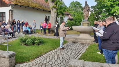 Bild: bsc
Eine passende Kulisse bot der Marienbrunnen zur letzten feierlichen Maiandacht der Pfarrei Maria Immaculata. Pfarrer Joseph (mitte) freute besonders die Gestaltung der Andacht durch die Kolpingsfamilie Friedenfels sowie das Mitwirken des Männergesangvereins „Frohsinns“ (rechts).