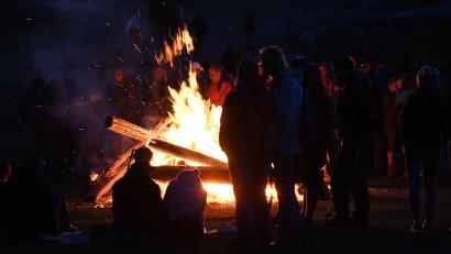 Bild: Angelika Warmuth/dpa/Archivbild
Menschen stehen bei einem Sonnwendfeuer zusammen.