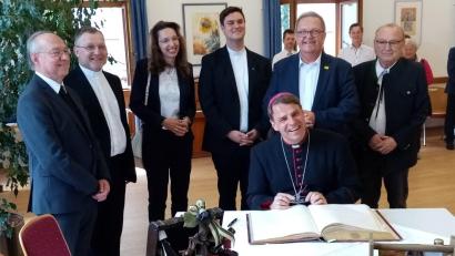 Bild: Martin Preuß/exb
Bischof Stefan Oster (sitzend) beim Eintrag ins Goldene Buch der Stadt Amberg.