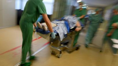 Symbolbild: Felix Kästle/dpa
Ein Mediziner-Team fährt in einer Klinik nach einer Operation einen Patienten im Bett durch den Klinikflur.