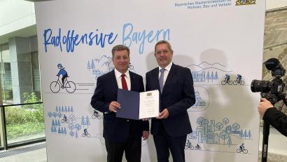 Bild: privat/exb
Bürgermeister Joachim Neuß durfte von Staatsminister Christian Bernreiter die entsprechende Urkunde in Empfang nehmen (Bild).Aufnahme in Radoffensive Bayern