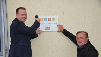 Bild: ak
Die Gemeinde hat das Siegel für Barrierefreiheit an öffentlichen Gebäuden erhalten. Bürgermeister Christian Porsch (links) und Gemeindebehindertenbeauftragter Markus Vogel bringen dies am Rathaus an.