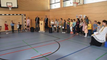 Bild: fz
Kinder musizieren, tragen Gedichte vor und singen bei der Einweihung ihrer "neuen Schule". Schulamtsdirektorin Christine Söllner (stehend links) spricht von einer "schulischen Brücke in die Zukunft".