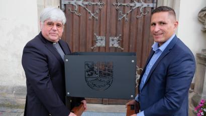 Bild: do
"Damit es im neuen Zuhause warm bleibt", sagte Bürgermeister Marcus Gradl zu Pfarrer Thomas Jeschner bei der Übergabe einer Feuerschale mit Stadtwappen als Abschiedsgeschenk der Stadt. Warm halten wollen beide auch das Thema des Pfarrheim-Neubaus.