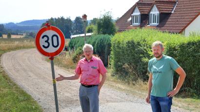 Bild: njn
Wo heute auf dem öffentlichen Feldweg, der früheren Ostmarkstraße, die Geschwindigkeit auf 30 km/h begrenzt ist, soll nach dem Willen von Bürgermeister Johannes Reger (links) zur Staubreduzierung nur noch 10 km/h gelten. Mit auf dem Bild der technische Angestellte Markus Meyer.