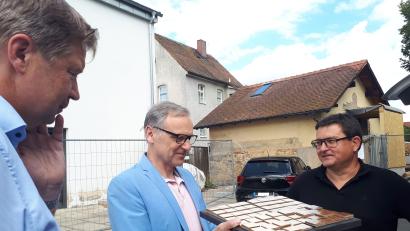 Bild: pz
Muster für die Gestaltung der Frontseite des künftigen Kolumbariums (im Hintergrund) hatte Planer Markus Braun (rechts, zusammen mit Stadtbaumeister Hubert Siller und Bürgermeister Bernd Sommer, von links) mitgebracht.