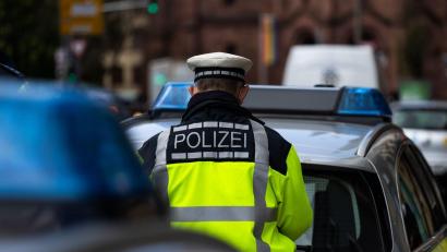 Bild: Philipp von Ditfurth/dpa/Symbolbild
Ein Polizeibeamter steht zwischen zwei Einsatzfahrzeugen der Polizei.