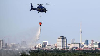 Bild: Britta Pedersen/dpa
Ein Hubschrauber der Bundespolizei wirft Wasser über der Brandstelle im Grunewald ab.