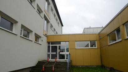 Bild: bey
Der Verbindungsgang wird bei Umsetzung des brandschutztechnischen Konzepts ein neues Betondach bekommen. Das erste Fenster links des Eingangs wird zugemauert. Fraglich ist noch, ob das untere Fenster im Treppenaufgang auch dem Brandschutzkonzept geopfert werden muss. Dann wäre der Hausgang dunkel.