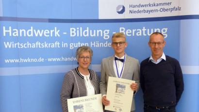 Bild:  Dietmar Völkl/exb
Jakob Völkl (Mitte) gewinnt in der Berufssparte „Bestattungsfachkraft“ den Leistungswettbewerb des Deutschen Handwerks auf Kammerebene für den Bezirk Niederbayern-Oberpfalz. Dafür erhalten er und sein Ausbildungsbetrieb, die Weidener Firma Bestattung Bauer, eine Auszeichnung. Die Geschäftsführer Martina Fuhrmann (links) und Wolfgang Dobler (rechts) nehmen diese entgegen.