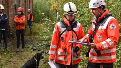 Bild: hcz
Die stellvertretende Weidener Staffelleiterin Nicole Liebeskind (von rechts) weist Metha Lahn aus Traunstein bei der "Trümmerprüfung" in das Szenario ein. Lahns schwarzer Labrador wartet derweil geduldig auf seinen Einsatz.