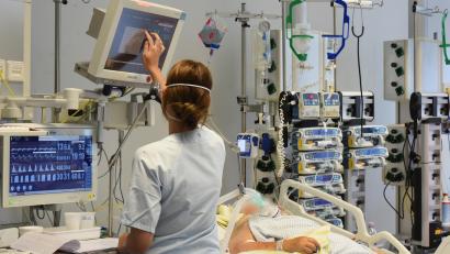 Symbolbild: Waltraud Grubitzsch
Auf der Intensivtherapie-Station steht eine Pflegekraft am Bett einer Patientin.