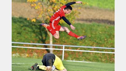 Bild: Hubert Ziegler
Torhüter Maximilian Hauer (am Boden) von der DJK Ensdorf hat den Ball sicher, Michael Mehringer vom SV Schmidmühlen hat keine Chance, an den Ball zu kommen, brilliert dafür mit einer artistischen Einlage.