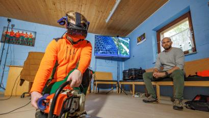 Bild: Forstbetrieb Fichtelberg/Martin Hertel/exb
Unterstützt durch Sicherheitsingenieur Sebastian Großmann von den Bayerischen Staatsforsten (rechts) trainiert Adrian Thoma den Umgang mit der Motorsäge in einem virtuellen Wald. Die VR-Brille auf dem Kopf zeigt dem Azubi beim Forstbetrieb Fichtelberg sein simuliertes Arbeitsumfeld.