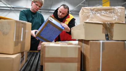 Symbolbild: Uwe Anspach/dpa
Mitarbeiter des Zolls und der Deutschen Post kontrollieren Pakete in einer Zollabfertigungsstelle.