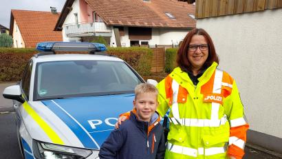 Bild: Polizeiinspektion Neustadt a. d. Waldnaab
Der Viertklässler Luis Talbot hat eine Fahrt im neuen Polizeiauto der Inspektion Neustadt gewonnen. Polizeihauptmeisterin Wettiner holte den Schüler zu Hause ab.
