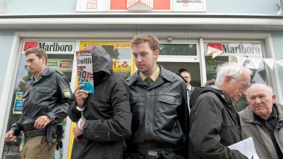 Archivbild: David Ebener/dpa
Im Jahre 2011 tötete der Flüchtige die 76-jährige Besitzerin eines Lotto-Ladens. Zwei Polizeibeamte führen einen der zwei "Lotto-Mörder" nach der Tatortbegehung im Jahr 2012 aus dem Lottogeschäft in Nürnberg.