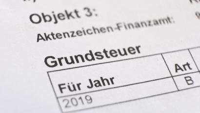 Symbolbild: Bernd Weissbrod/dpa
Ein Bescheid über die Grundsteuer liegt auf einem Schreibtisch.
